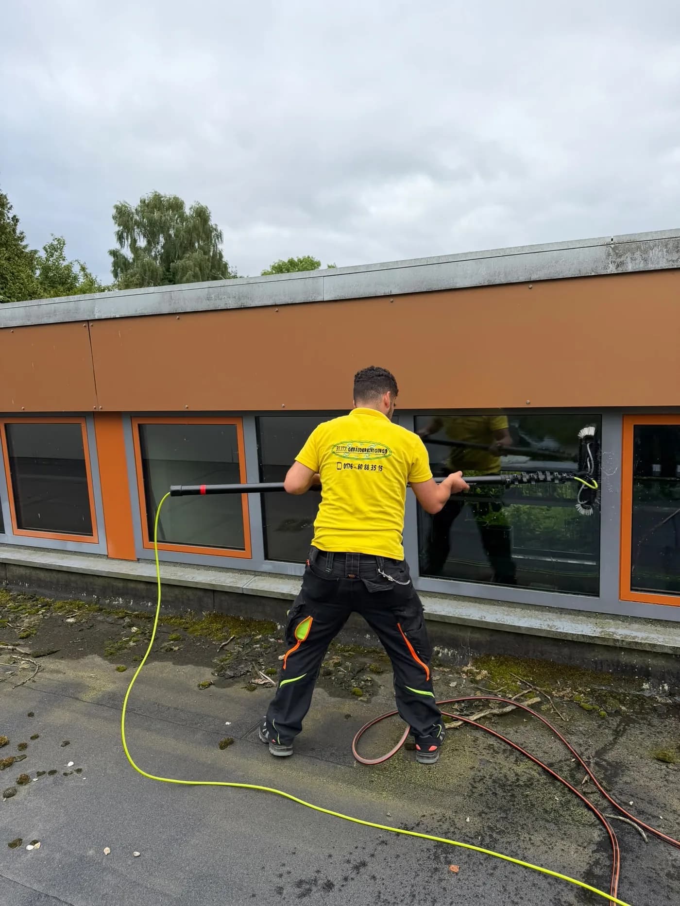 Teleskopbürste mit Wasserzuführung bei der Reinigung einer Fensterfront