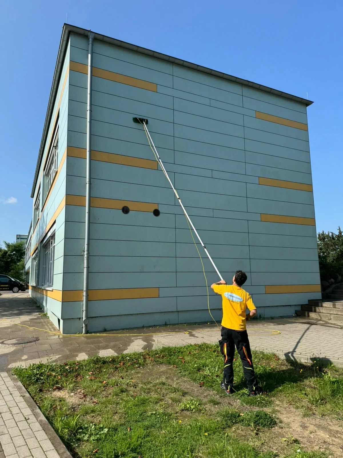 Fensterreinigung mit Teleskopstange an einem mehrgeschossigen Gebäude